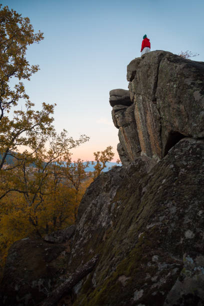 istock Back view of young man doing parkour standing on rock in sunset 924182272