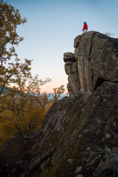 istock Back view of young man doing parkour standing on rock in sunset 924182320