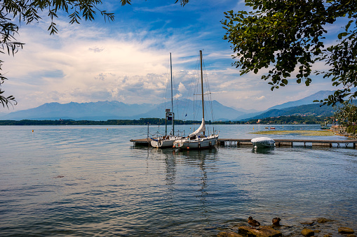 Two yachts moored at small wooden pier under beautiful sky on Lake Viverone in Piedmont, Northern Italy.