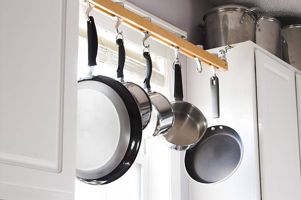 Stainless steel pots and pans hanging from hooks in kitchen  stock photo