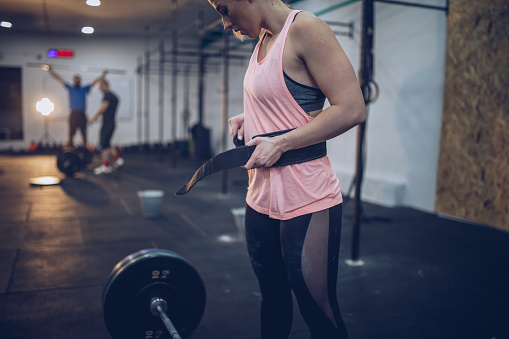 One woman in gym, preparing for training with weights.