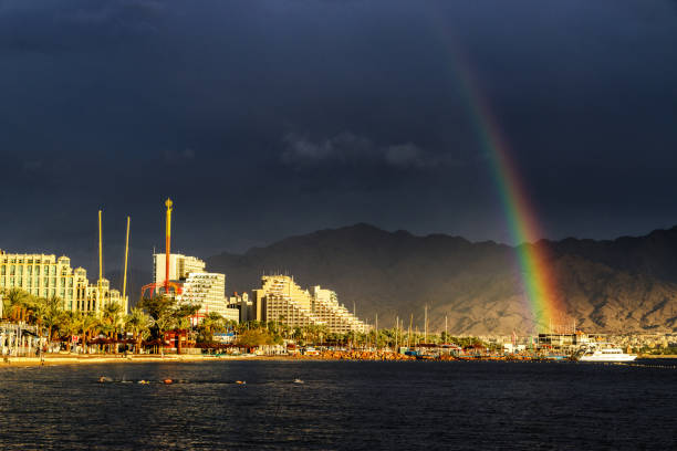 istock Rainbow and dark rain clouds over lightened beach in Eilat, Israel 924194568