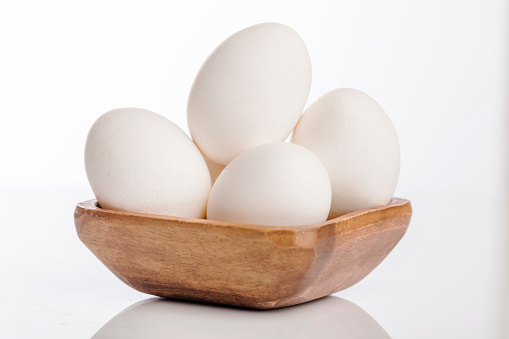 Wooden cup of white eggs on white background.