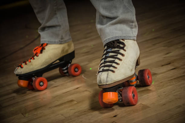 A close up of a man’s feet wearing skates standing on a roller rink.