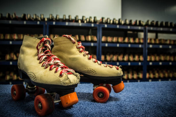 Roller skates A pair of roller-skates off center with rows of skated in the background. roller rink stock pictures, royalty-free photos & images