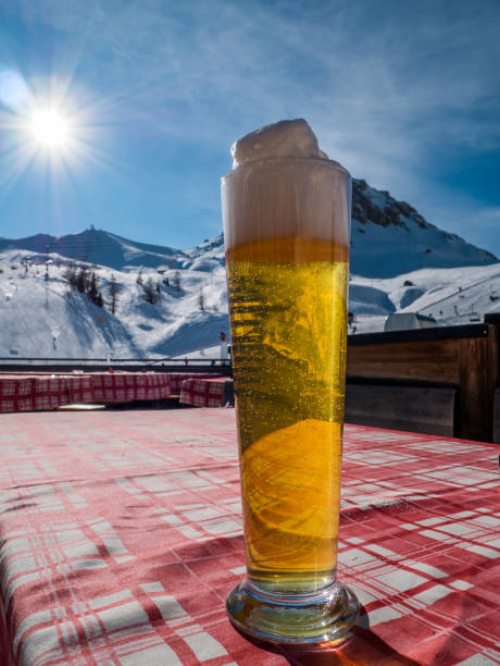 vaso de cerveza de bosquejo grande sobre una mesa en los alpes. colina de esquí o pendiente y luz en el fondo. - beer ski apres ski snow fotografías e imágenes de stock