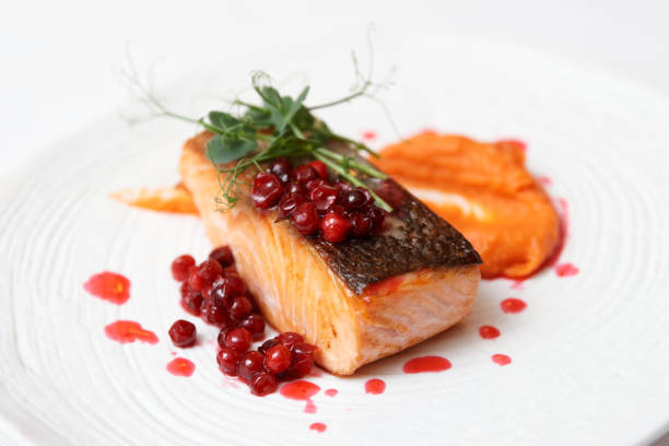 Fried salmon steak with pumpkin puree, berry sauce and herbs