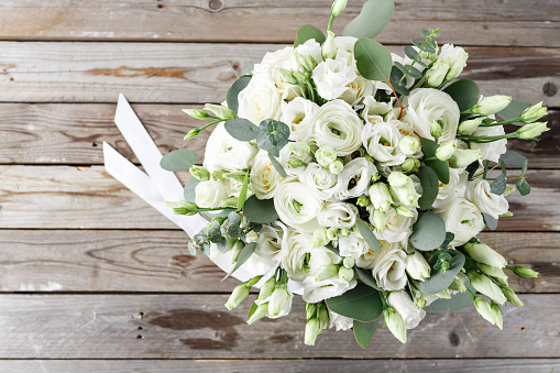 Close up of lush wedding bouquet of white flowers and greenery on wood background, copy space. Bridal bouquet