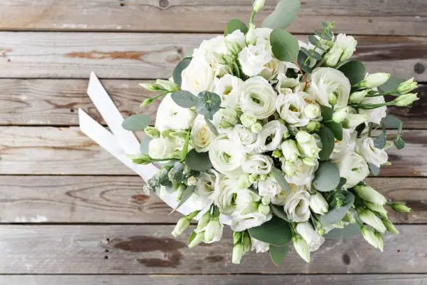 Wedding bouquet of white roses and buttercups on a wooden table. top view.