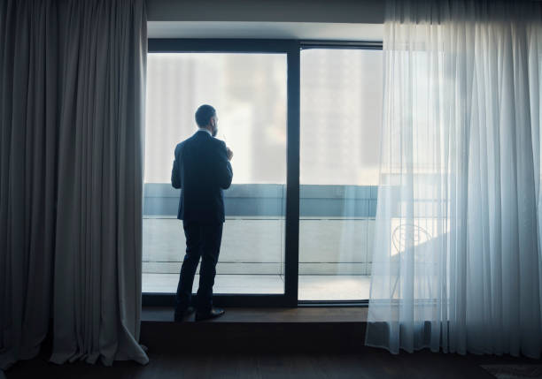 istock Businessman looking through window of hotel 924218520