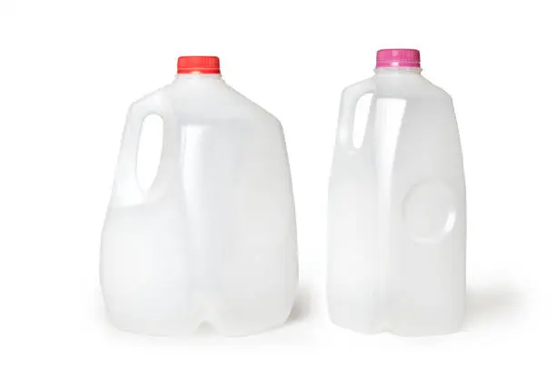 Horizontal photograph of 2 milk jugs, half gallon and gallon jug, lined up in a row. The labels are off and the jugs are empty and placed on a white background.