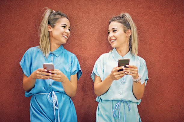 istock Happy twin sisters are texting and looking each other 924231192