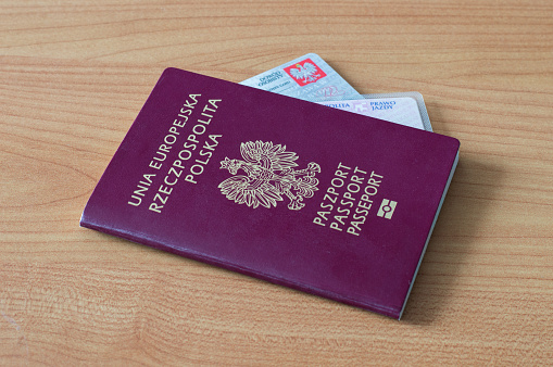 Closeup high angle photo of a French biometric passport just inside a zippered pocket of a tan leather handbag. White background