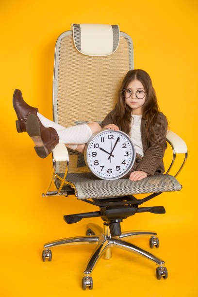 istock Little brunette girl with clocks in chair 924257480
