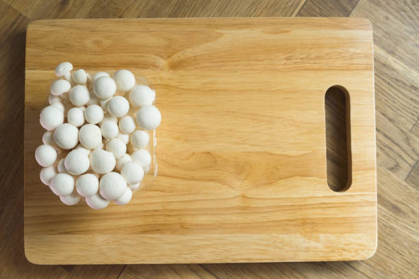 Enoki mushrooms on chopping wooden board background.White mushrooms, stock photo