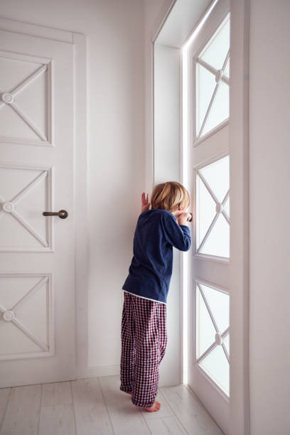 istock curious young boy looks into the ajar door 924270180