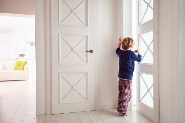 curious young boy looks into the ajar door - snooper imagens e fotografias de stock