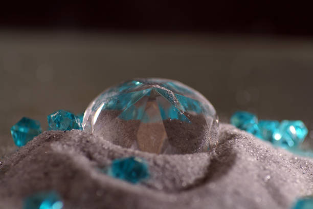 of a bottle of perfume tied with a festive ribbon on a snowy wooden surface with balls, cones and a snowman against the background of blurry lantern lights and white balls in the background.
