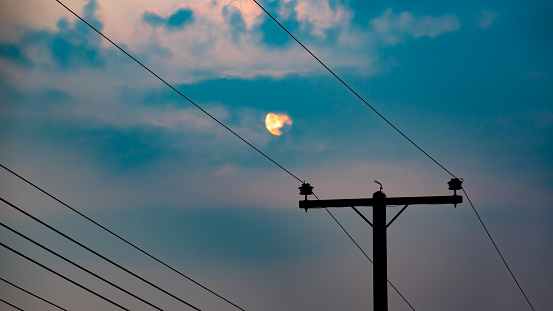 Electric pole and electric cable on sky blue and cloud on dark morning