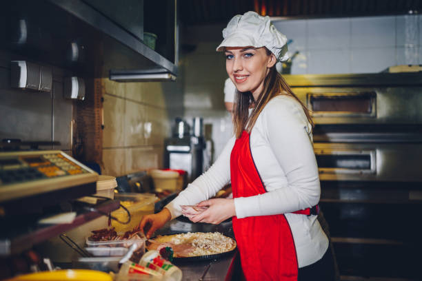 istock Woman making pizza in the restaurant kitchen 924279132