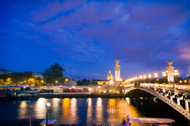 Pont Alexandre III bridge illuminated and Seine River at night. Paris, France