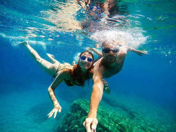 istock Joyful happy couple having fun underwater with selfie stick. 924294582