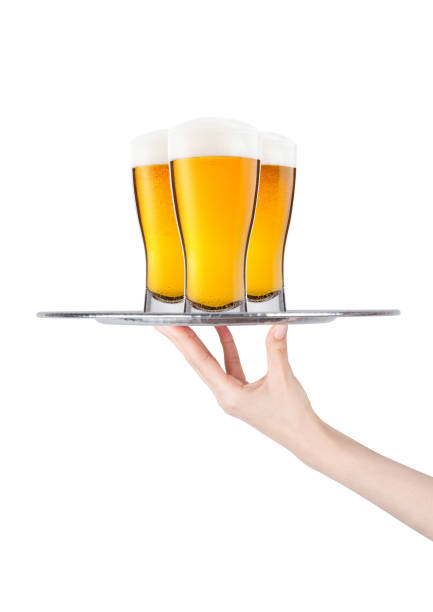 Hand holds tray with lager beer glasses with foam and dew isolated on white background
