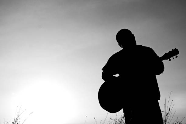 istock Abstract beautiful man playing Guitar in the foreground on clear sky background. 924312214