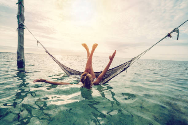 Girl relaxing on sea hammock tropical climate View of a young woman relaxing on hammock over the water, people travel vacations concept. Shot in the Gili Islands, Lombok, Indonesia lombok indonesia stock pictures, royalty-free photos & images