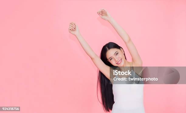 Happy And Cheerful Smiling Asian 20s Woman Raising Hands Up For Positive Feeling And Celebration Isolated Over Pink Background Stock Photo - Download Image Now