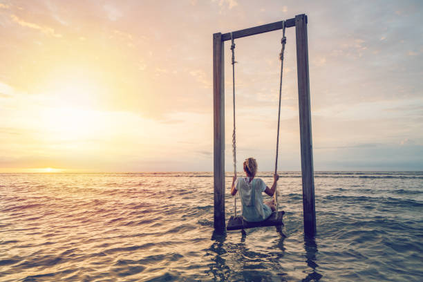 Caucasian female playing on swing by the sea at sunset, Indonesia Young woman swinging over the sea at sunset, beautiful and idyllic landscape. People travel vacations concept. gili trawangan stock pictures, royalty-free photos & images