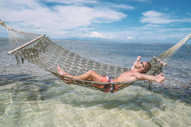 istock Cheerful man relaxing on sea hammock arms outstretched 924323162