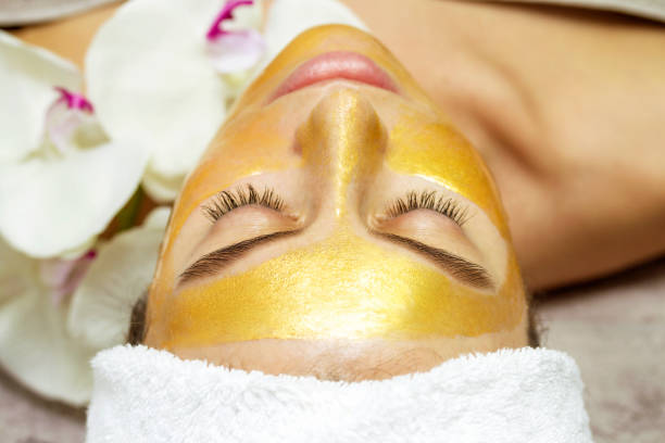 Beautiful woman with facial mask at beauty salon Portrait of a beautiful woman getting facial care at spa salon. Gold Facial Kit for skin stock pictures, royalty-free photos & images