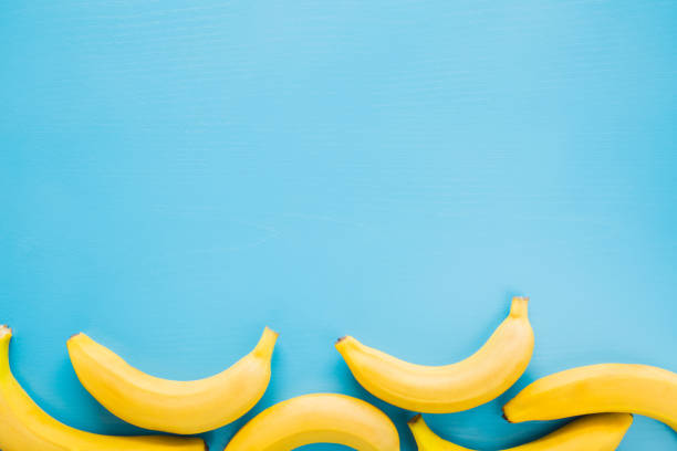 bonita, fresca, amarela banana sobre o fundo azul. conceito de comida saudável de doce. zombe para ofertas de frutas, como fundo de publicidade ou web, ou outras ideias. lugar vazio para texto ou logotipo. - banana bunch yellow healthy lifestyle - fotografias e filmes do acervo