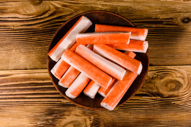 istock Ceramic plate with crab sticks on wooden table. Top view 924345972