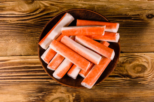 Ceramic plate with crab sticks on wooden table. Top view stock photo