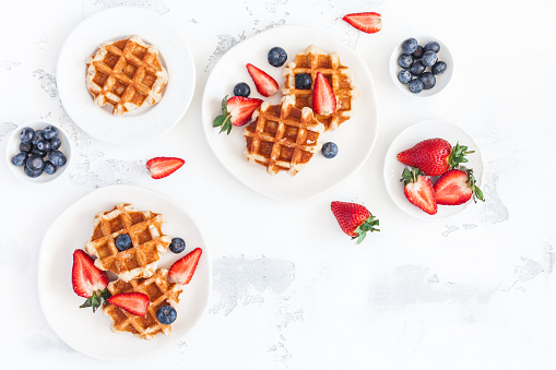 Belgian waffles with fresh strawberry and blueberry on white background. Flat lay, top view, copy space