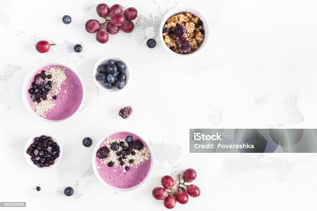 Breakfast with muesli, blueberry smoothie, fruits. Flat lay, top view Breakfast with muesli, acai blueberry smoothie, fruits on white background. Healthy food concept. Flat lay, top view, copy space Yogurt Stock Photo