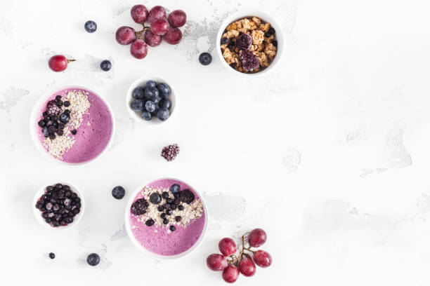 Breakfast with muesli, blueberry smoothie, fruits. Flat lay, top view Breakfast with muesli, acai blueberry smoothie, fruits on white background. Healthy food concept. Flat lay, top view, copy space bilberry fruit stock pictures, royalty-free photos & images