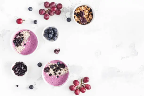 Breakfast with muesli, acai blueberry smoothie, fruits on white background. Healthy food concept. Flat lay, top view, copy space