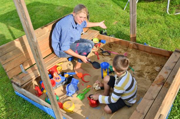 Family child boy mother playing in the sandpit in the summer stock photo