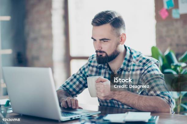 Concept Of Having A Break At Work Concentrated Calm Peaceful Serious Office Worker Watching Carefully A Video On The Internet Using His Laptop And Drinking Tea Stock Photo - Download Image Now