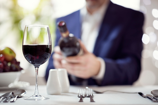 Businessman reading red wine bottle label in restaurant concept for business lunch or dinner meeting