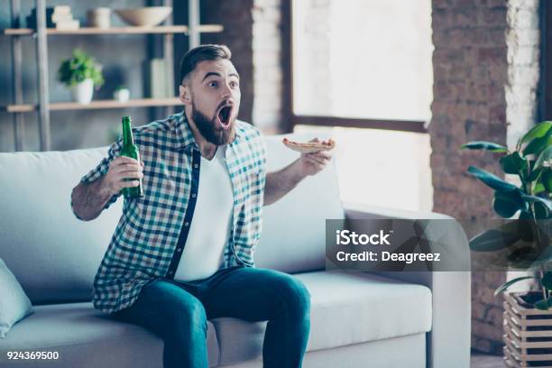 Omg Ziel Verrückte Lustige Glücklich Aufgeregt Erstaunt Erstaunt Kerl Im Karierten Hemd Und Jeans Bekleidet Er Isst Pizza Und Bier Trinken Auf Dem Sofa Sitzen Und Beobachtete Finale Des Sportspiel Stockfoto und mehr Bilder von Fernseher