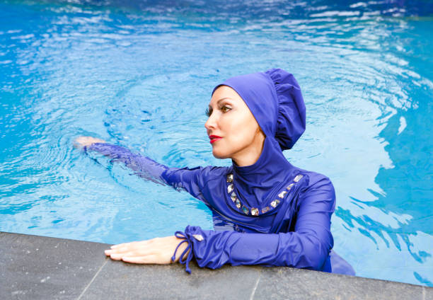 有魅力的婦女在穆斯林泳裝 burkini 在水池 - 回教泳裝 圖片 個照片及圖片檔