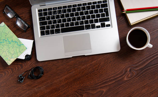 Notebook with hot coffee and map on wood table Notebook with hot coffee, map, notepad, glasses, headphones and pencils on brown wood table. Concept of preparation for rest and travel. escribir stock pictures, royalty-free photos & images