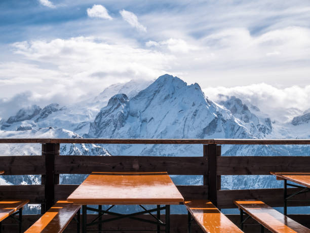 vista de montañas nevadas del restaurante de los alpes. almuerzo de esquí bajo el sol. mesas vacías y asientos en primer plano. - apres ski ski snow mountain fotografías e imágenes de stock