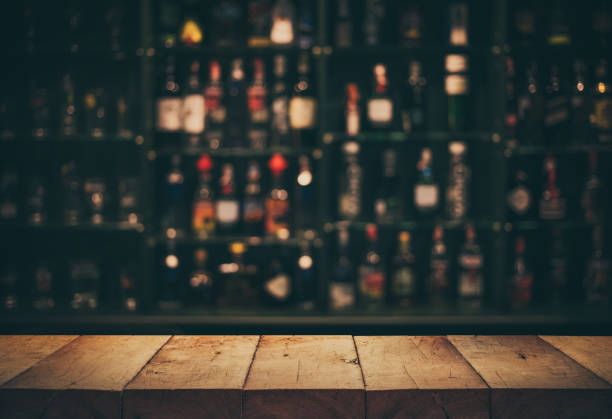 Empty the top of wooden table with blurred counter bar and bottles Background Empty the top of wooden table with blurred counter bar and bottles Background /for your product display bar counter photos stock pictures, royalty-free photos & images