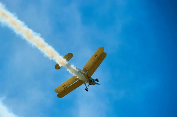 Vintage single engine propeller biplane aircraft flying against sky - bottom view