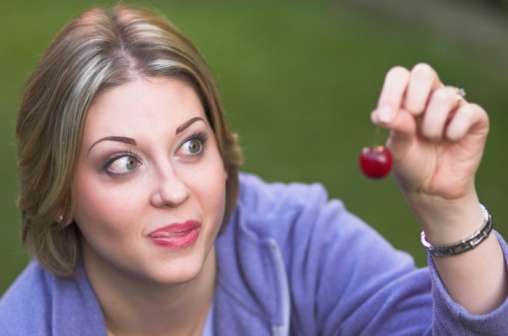 A woman licks her lips ready to eat a cherry